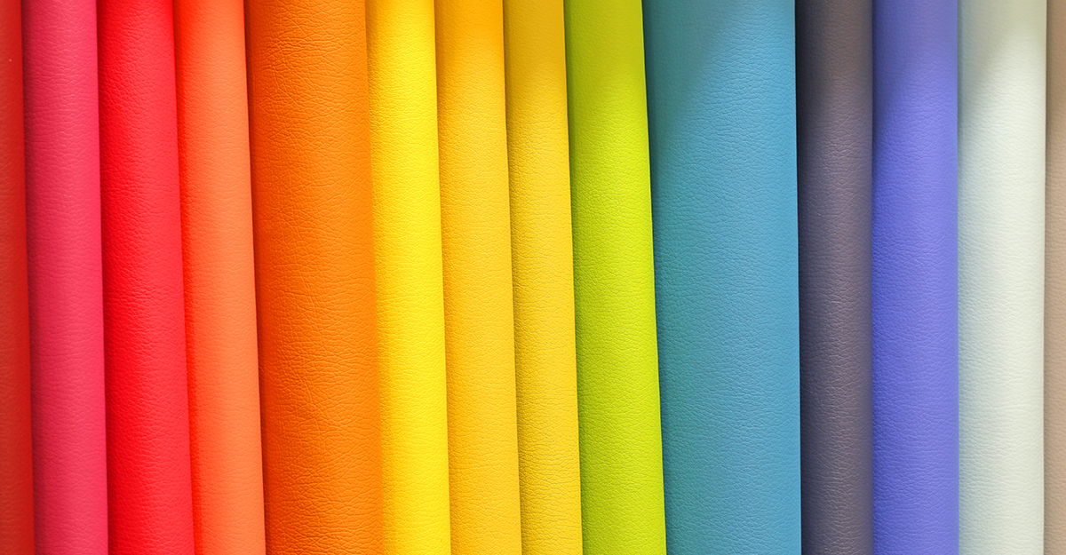 Barevné látky mnoha jasných a živých barev na prodej v obchodě specializovaném na látky pro zpracování oděvů