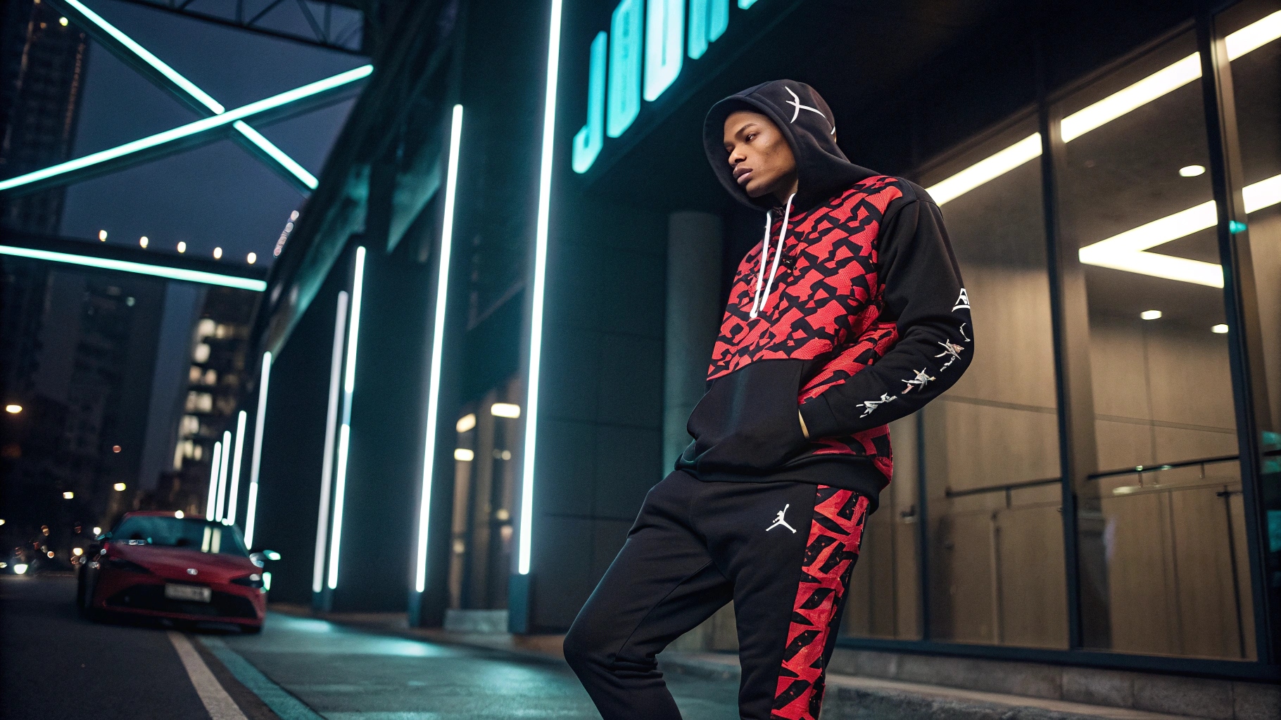  A model wearing a custom-designed Jordan-inspired hoodie with bold graphics, paired with luxury joggers, set against a sleek urban backdrop with neon lighting, emphasizing exclusivity and hype culture.